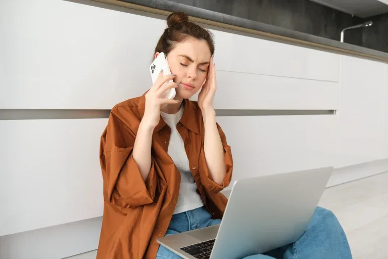 Personne au téléphone devant un ordinateur portable.
