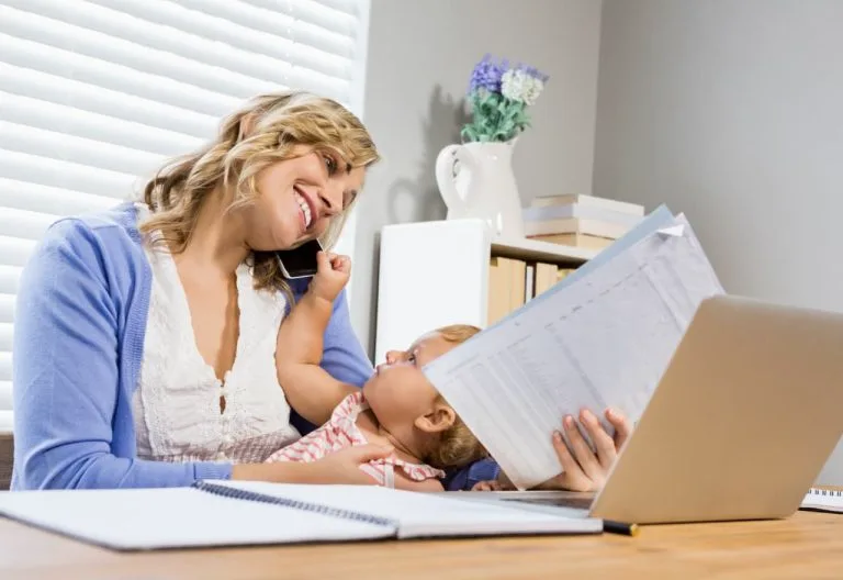 Personne examinant des documents avec un bébé sur ses genoux.