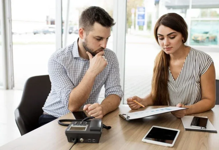 Couple examinant des documents avec une calculatrice.
