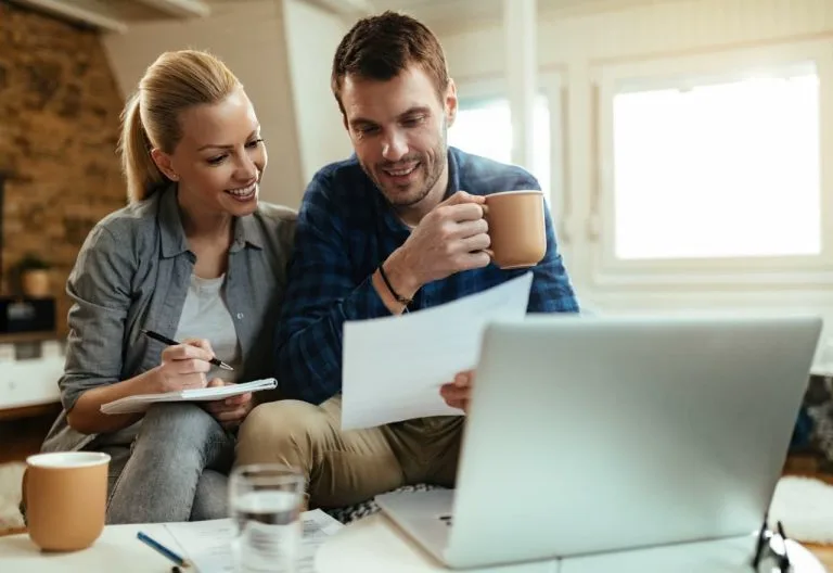 Couple consultant des documents devant un ordinateur.