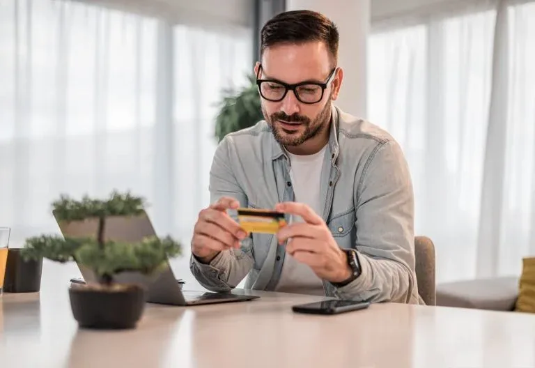 Personne tenant une carte devant un ordinateur.